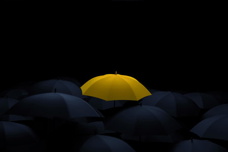 Yellow umbrella stands out among black umbrellas, creative idea. Unique yellow umbrella among many dark ones. Standing out from crowd, individuality and difference concept.の写真素材