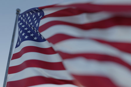 Waving United States flag on a pole against clear blue sky, symbolizing patriotism, freedom, democracy, and national pride. USA flag, macroの写真素材