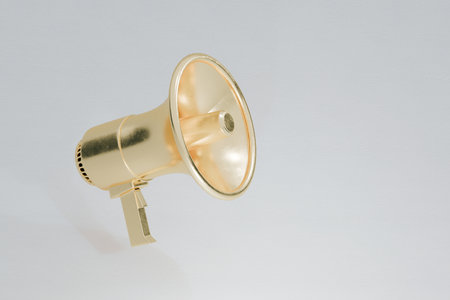 Golden megaphone on a gray background - communication, marketing, promotion, and public announcements, representing leadership, influence, and spreading important messages.の写真素材