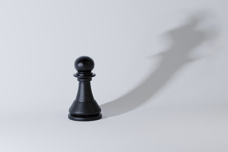 Black chess pawn casting a shadow of a crown, symbolizing ambition, potential, leadership, and transformation from ordinary to extraordinary with vision. Strategy leader, creative idea. King, conceptの写真素材
