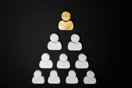 Golden figure at the top of a human pyramid on black background, symbolizing career growth, leadership, hierarchy, HR management, employee development, and professional success. Teamwork, creativeの写真素材