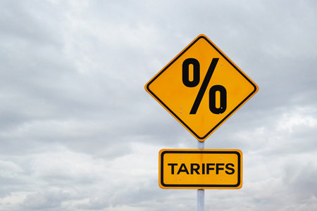 Tariffs. Sanctions and tariff increases, creative idea. Yellow tariffs sign on gray cloudy sky, concept.の写真素材