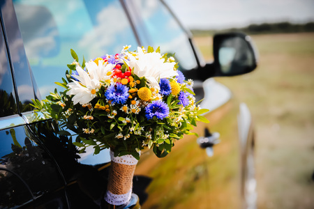 Wedding bouquet in a black car door standing outdoorsの写真素材