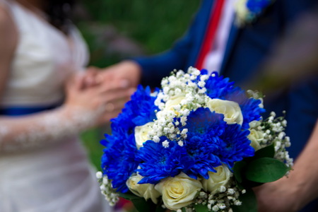 Hands and rings on the background of the costume of the groom and the bride's wedding bouquetの写真素材