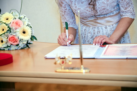 Hands and rings on the background of the costume of the groom and the bride's wedding bouquetの写真素材