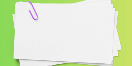 Blank white sheets of paper with purple paper clip on green background