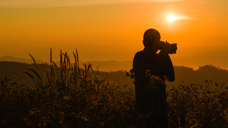 Silhouette of a young who like to travel and photographer, taking pictures of the beautiful moments during the sunset ,sunrise.の写真素材