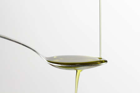 Pouring extra-virgin olive oil on a spoon, isolated on clear backgroundの写真素材