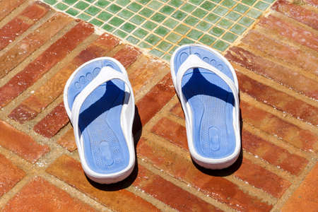 Close-up of flip flop slippers color blue and white beside a pool shower. On holidays.の写真素材