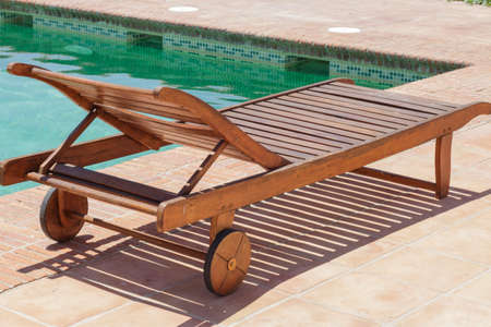 Wooden sun recliner at the edge of a poolの写真素材