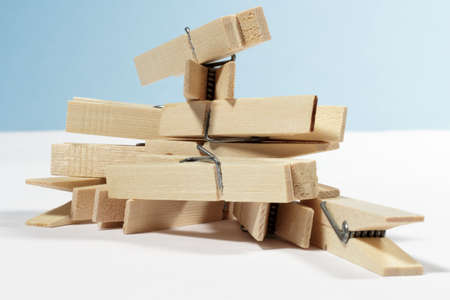 Several wooden clothespins heaped up, on white floor and blue backgroundの写真素材