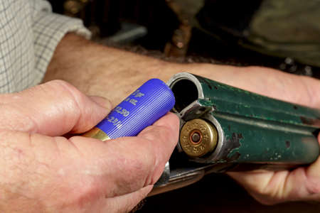 Man putting ammunition into an old double-barreled shotgunの写真素材