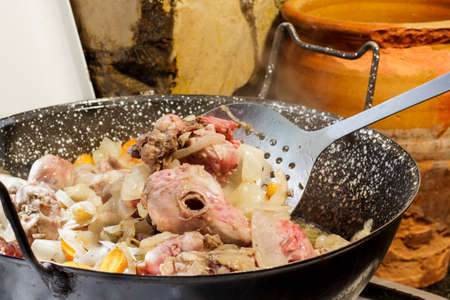 Stirring wild rabbit meat with a skimmer, while is cooked in a casseroleの写真素材