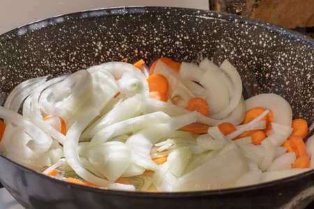 Onion rings and carrot slices being sauteed in casseroleの写真素材