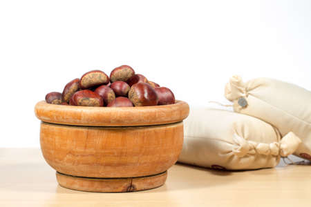 Wooden bowl full of chestnuts beside two sacks of chestnut flourの写真素材