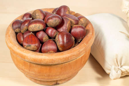 Wooden bowl full of chestnuts beside a small sack of chestnut flourの写真素材