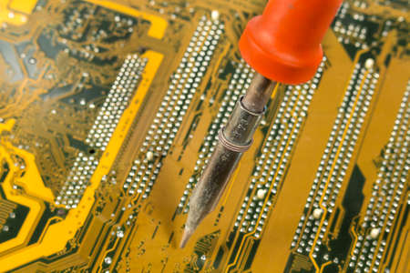 Close-up of soldering iron over a printed circuit board