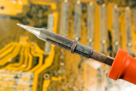Soldering iron with red handle over a motherboardの写真素材