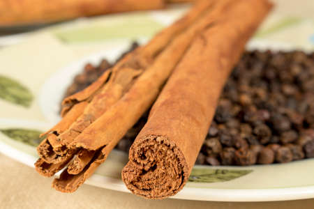 Cinnamon sticks and black pepper grains on decorated dish