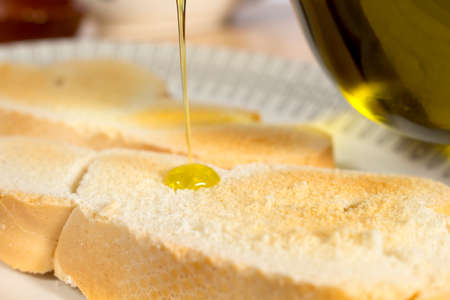 Pouring Extra Virgin olive oil on slices of toasted bread. Mediterranean breakfastの写真素材