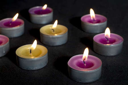 Small scented candles with metal base, smelling lilacs and green apples, on dark floorの写真素材