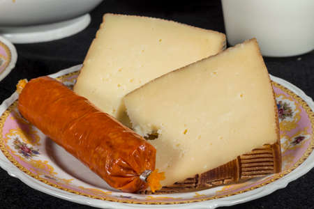 Manchego Curado cheese slices beside a sobrassada, typical majorcan sausage