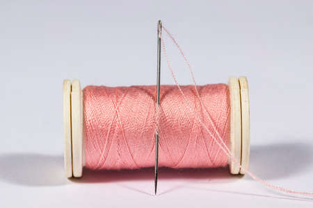 Threaded needle in a pink spoolの写真素材