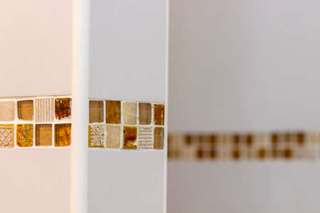 Detail of the brown edging in the white tiles of a showerの写真素材