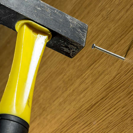 Hammering nail into a wooden surface