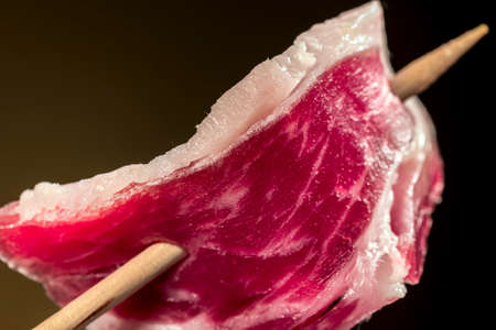 Slice of Iberian ham on a wooden skewerの写真素材
