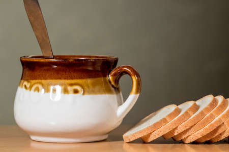 Bowl of vegetable soup beside slices of white breadの写真素材