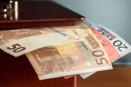 Different euro banknotes sticking out of a metal moneyboxの写真素材