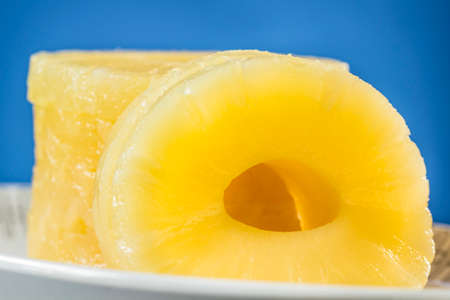 Canned pineapple slices, preserved at its own juice, on oval dish and blue backgroundの写真素材