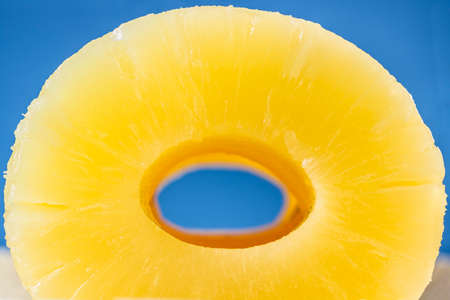 Close-up view of the hole in the middle of several canned pineapple slices, on blueの写真素材