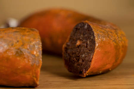 Close-up of traditional homemade blood sausage, covered by red lard, on wooden tableの写真素材