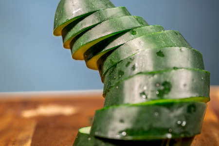 Column made of slices of cucumber on wooden floor and clear bluer backgroundの写真素材