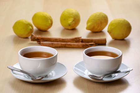 Cups of Pu-erh tea, known as red tea in China but as black tea in the West, in front of lemons and cinnamon sticks の写真素材