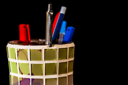 Close-up of colorful crystal pencil holder with pens, pencils and marking pens on black backgroundの写真素材