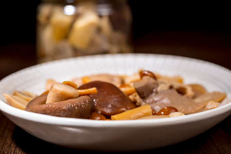 Oval dish with selection of different boiled mushrooms in front of other pot. Preserved gourmet foodの写真素材