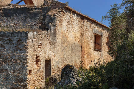 Stone walls of abandoned old farmhouse, beside a crag with scrubsの写真素材