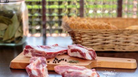 Raw pork ribs over a dark wooden kitchen board, in front of a windowの写真素材