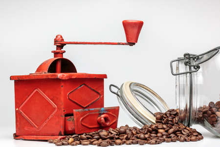 Ancient manual grinder beside coffee beans, on whiteの写真素材
