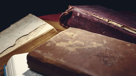 Ancient knowledge background: Close-up of heap of age-worn books, on black