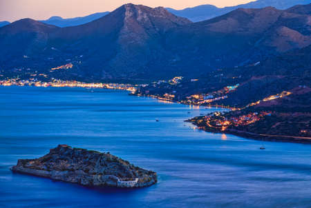 The island of Spinalonga and Elounda in the background at sunset in Crete Greeceの写真素材