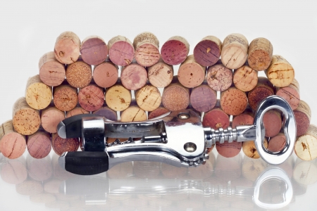 Corkscrew against of the stack of wine corks with reflection on the glass tableの写真素材