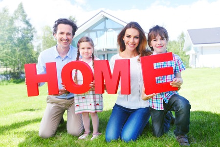 happy holding home letters in front of their houseの写真素材