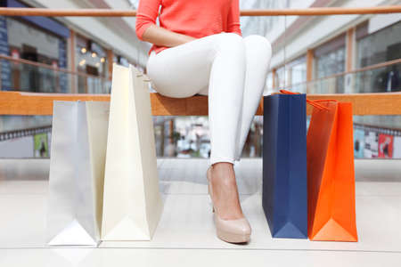 Tired woman sitting near her shopping bags in mallの写真素材