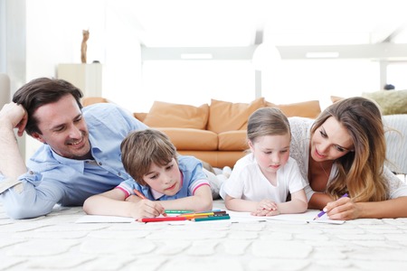 happy family drawing pictures with coloring pencilsの写真素材