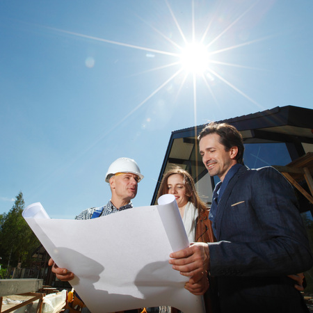 foreman shows house design plans to a young coupleの写真素材