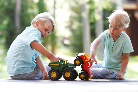 two brothers playing outdoors with toy carsの写真素材